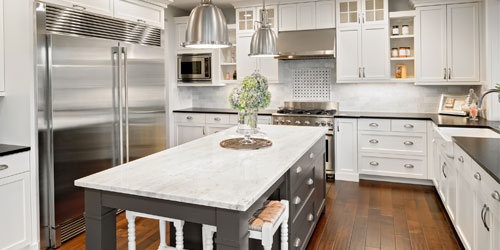 Newly remodeled kitchen with white floor to ceiling cabinets and a center island of dark cabinets